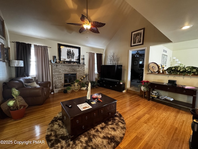 living area featuring ceiling fan, a fireplace, high vaulted ceiling, and wood finished floors