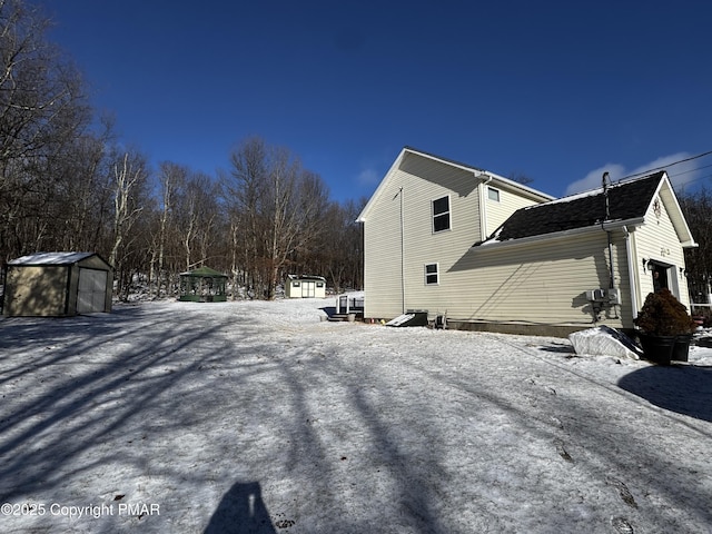 view of snow covered exterior featuring a shed and an outdoor structure