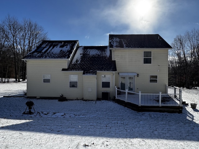 snow covered back of property with a wooden deck and central air condition unit