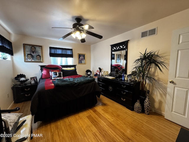 bedroom featuring baseboards, wood finished floors, visible vents, and a ceiling fan