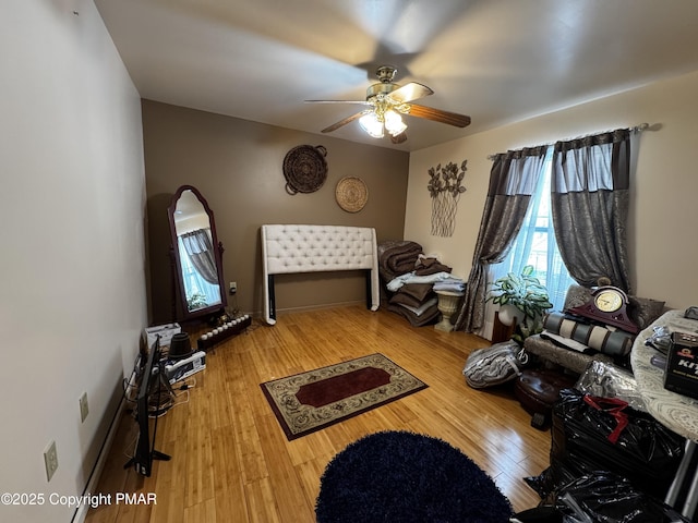 bedroom with ceiling fan, wood finished floors, and baseboards