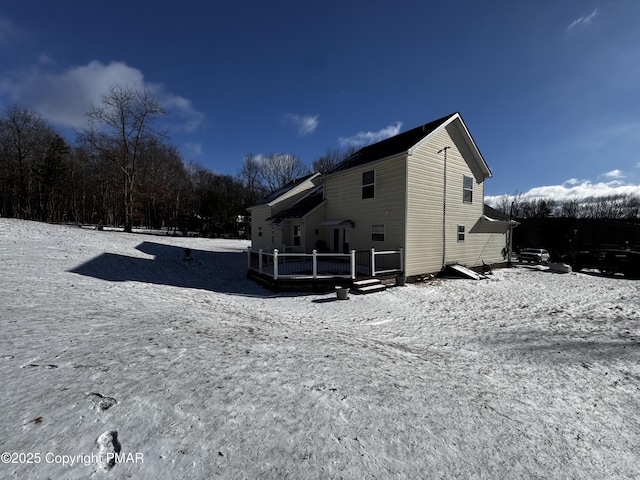 snow covered back of property featuring a deck