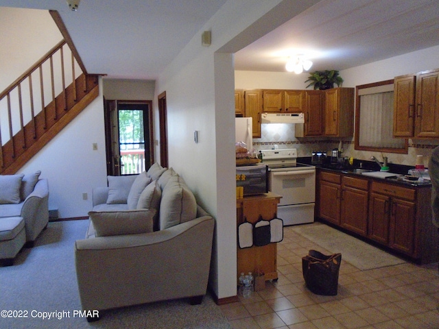 101 Withywindle Way, Tamiment, PA 18371 - kitchen with white electric range, under cabinet range hood, open floor plan, tasteful backsplash, and brown cabinetry