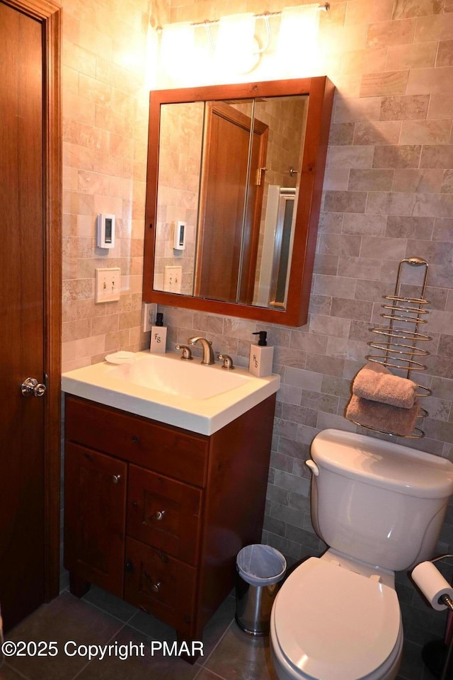 bathroom featuring toilet, vanity, tile walls, backsplash, and tile patterned floors