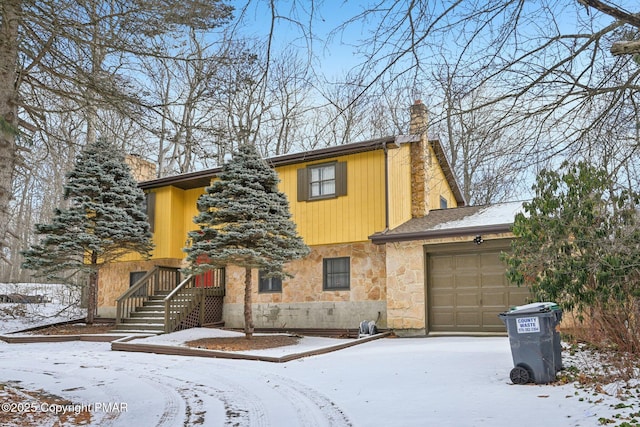 view of front of house featuring an attached garage, stone siding, and a chimney