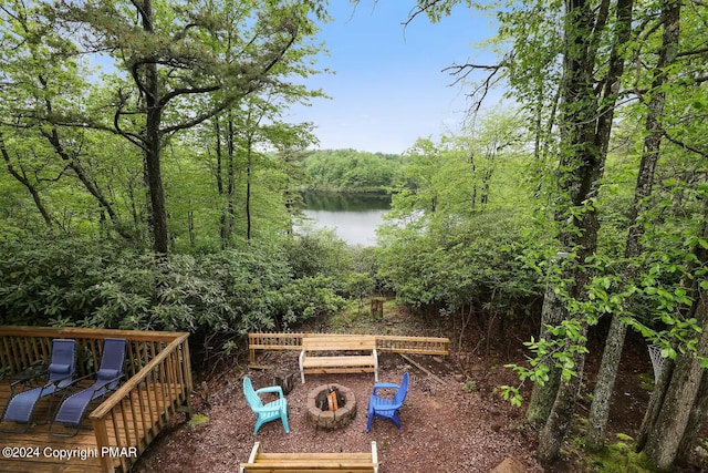 view of yard featuring an outdoor fire pit, a water view, and a view of trees