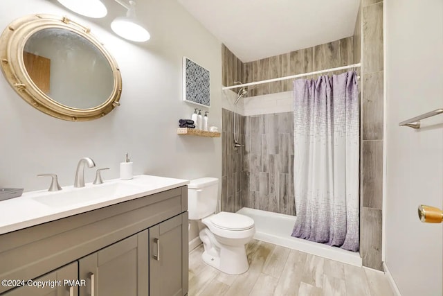 full bathroom with vanity, a tile shower, and toilet