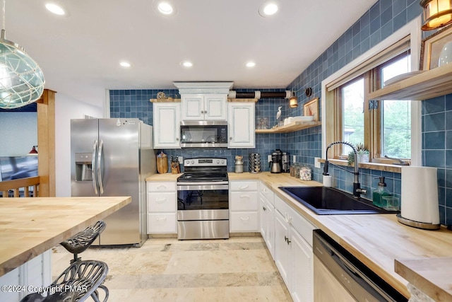 kitchen featuring backsplash, white cabinetry, stainless steel appliances, and a sink