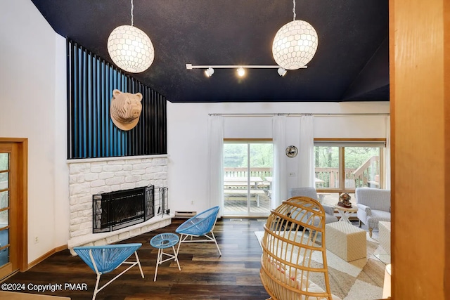 living area with baseboards, vaulted ceiling, wood finished floors, and a stone fireplace