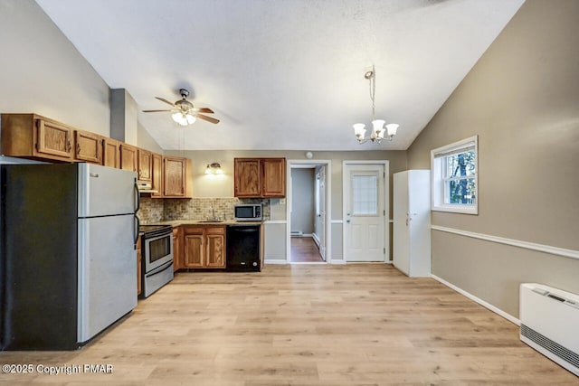 kitchen featuring vaulted ceiling, appliances with stainless steel finishes, decorative light fixtures, backsplash, and light hardwood / wood-style floors