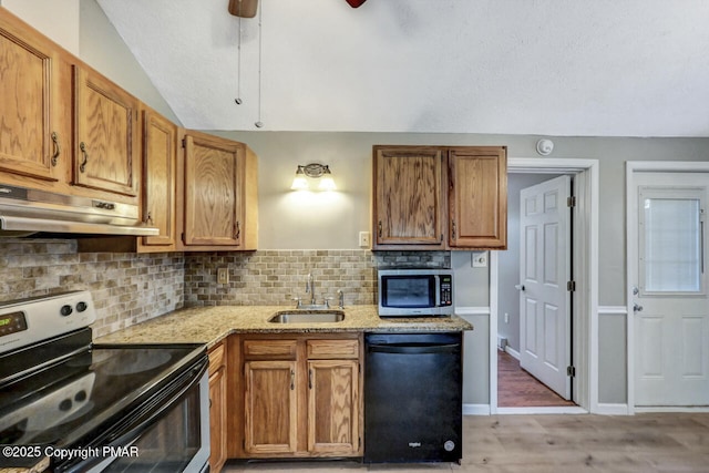 kitchen with sink, appliances with stainless steel finishes, light stone countertops, decorative backsplash, and light wood-type flooring