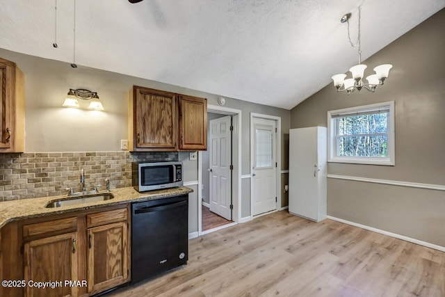 kitchen with vaulted ceiling, decorative light fixtures, tasteful backsplash, black dishwasher, and sink