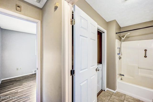 bathroom with baseboard heating, bathtub / shower combination, and a textured ceiling