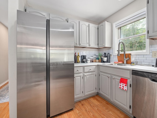 1533 Black Birch Way, Tobyhanna, PA 18466 - kitchen with stainless steel appliances, light wood-style flooring, backsplash, light countertops, and white cabinetry