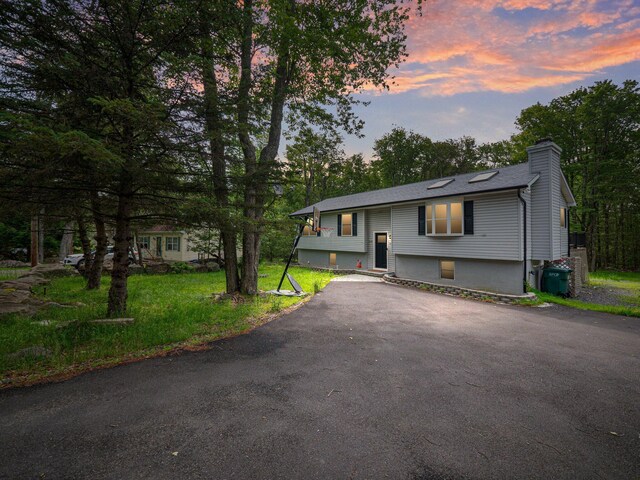 1533 Black Birch Way, Tobyhanna, PA 18466 - bi-level home featuring a chimney, asphalt driveway, and view of scattered trees