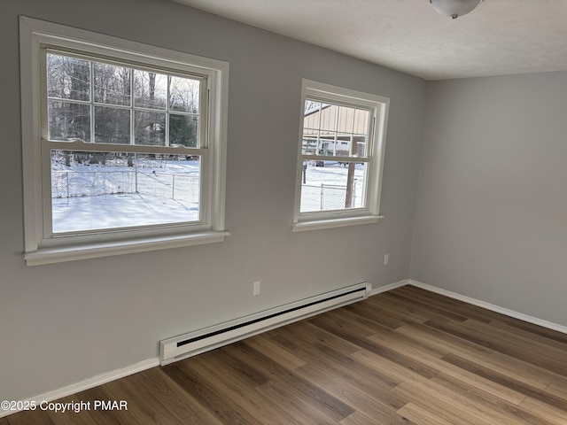 empty room with a baseboard radiator, a textured ceiling, baseboards, and wood finished floors