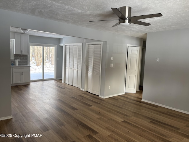 interior space featuring baseboards, dark wood-style floors, access to exterior, a textured ceiling, and two closets