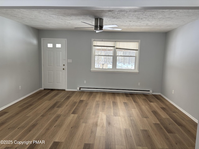 interior space featuring a textured ceiling, ceiling fan, a baseboard radiator, wood finished floors, and baseboards