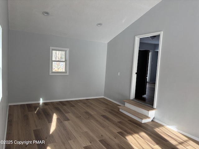 unfurnished room with vaulted ceiling, wood finished floors, and baseboards