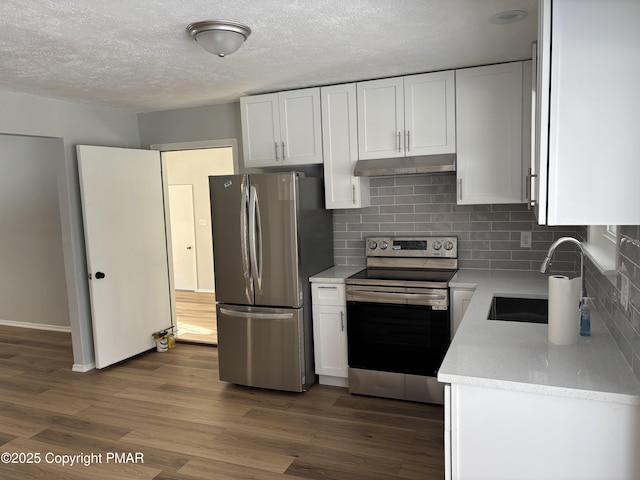 kitchen featuring dark wood-style flooring, backsplash, appliances with stainless steel finishes, white cabinetry, and a sink