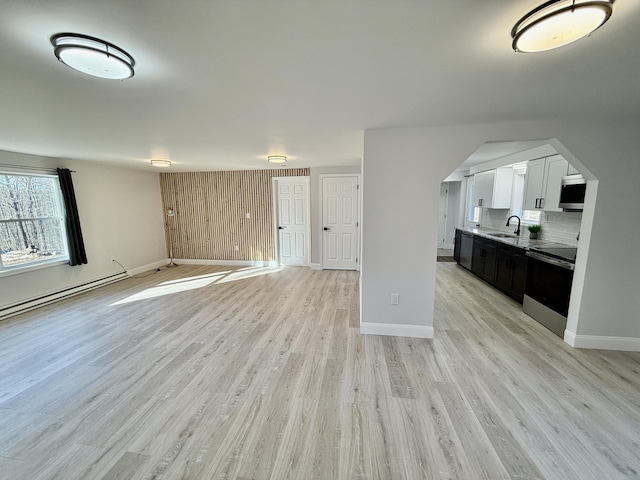 unfurnished living room with baseboards, light wood-type flooring, and a sink