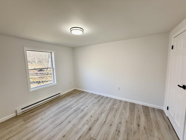 spare room with light wood-type flooring, a baseboard heating unit, and baseboards