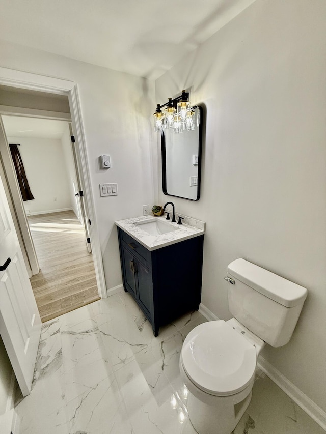 bathroom with baseboards, toilet, marble finish floor, and vanity