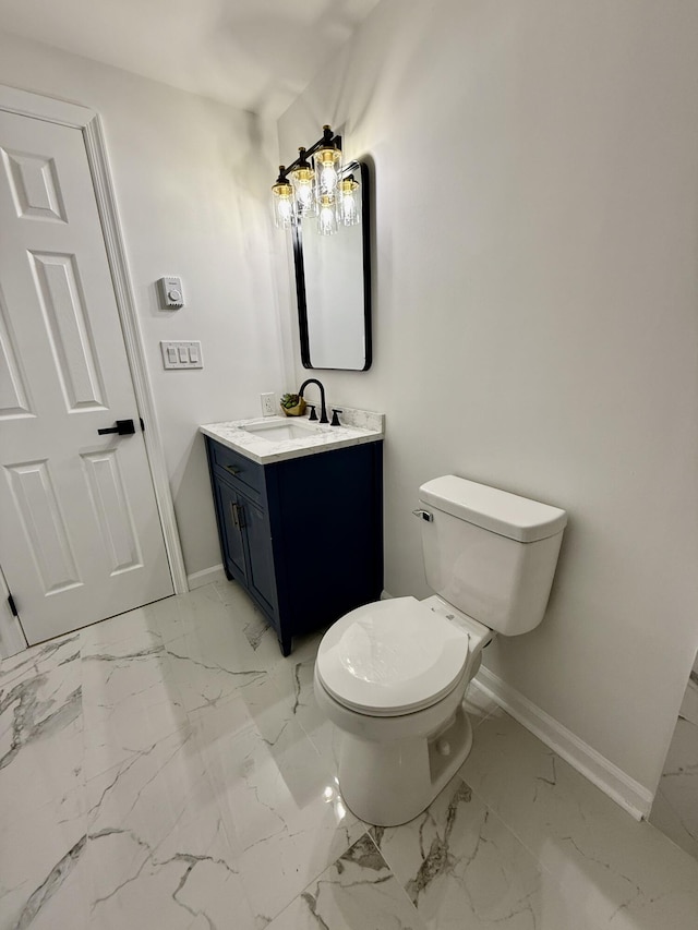 bathroom with marble finish floor, toilet, vanity, and baseboards