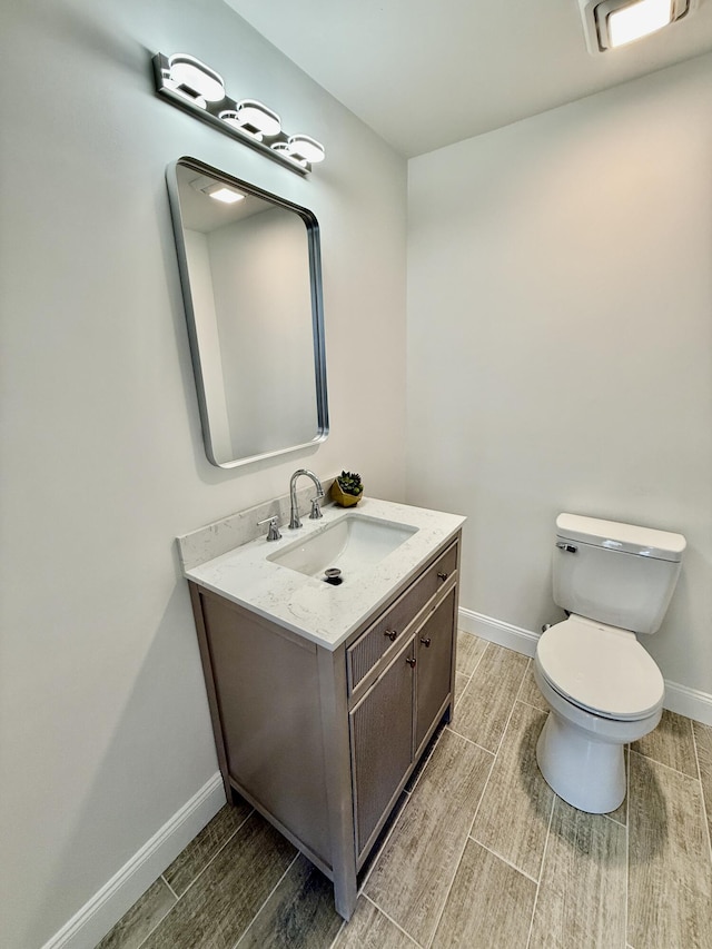 half bath featuring baseboards, vanity, toilet, and wood tiled floor