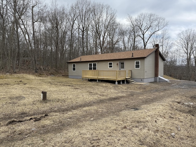 back of house featuring a chimney, roof with shingles, and a wooden deck