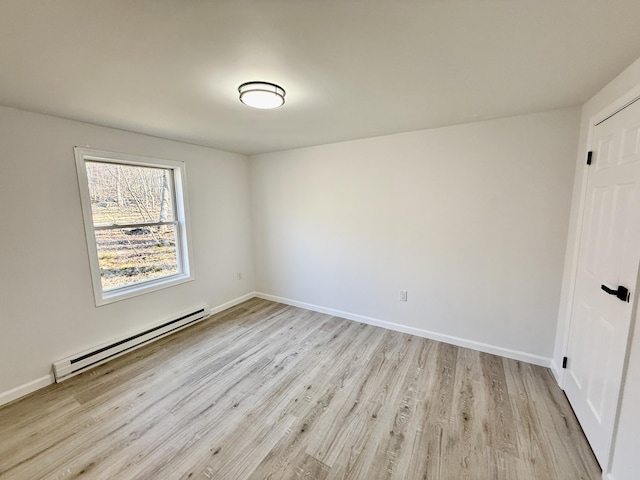 empty room featuring baseboards, baseboard heating, and light wood finished floors