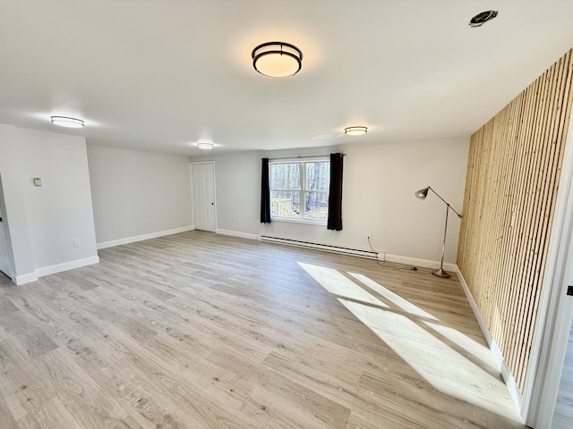 spare room featuring light wood finished floors, baseboards, and baseboard heating