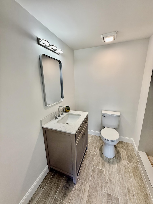 bathroom with vanity, toilet, baseboards, and wood tiled floor