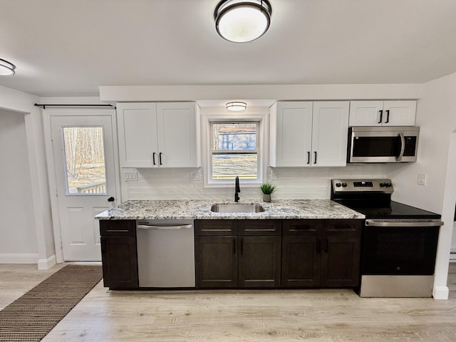 kitchen featuring a sink, decorative backsplash, light stone counters, and stainless steel appliances