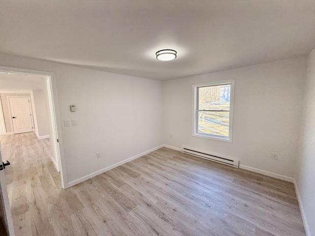 unfurnished room featuring baseboards, light wood finished floors, and a baseboard radiator