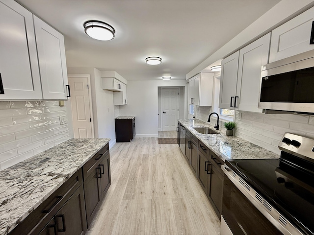 kitchen featuring a sink, light stone countertops, light wood-style floors, and stainless steel appliances