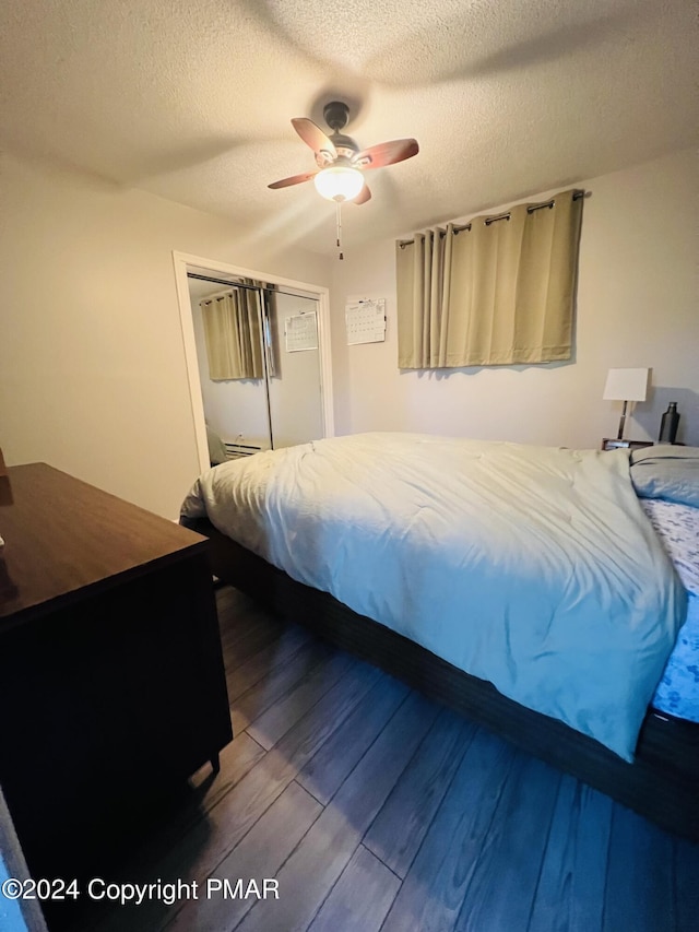 bedroom with a textured ceiling, a closet, wood finished floors, and a ceiling fan