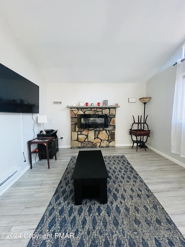 living area featuring lofted ceiling, a baseboard heating unit, wood finished floors, and baseboards