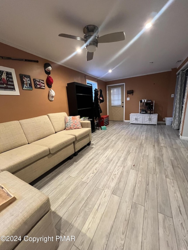 living room featuring a ceiling fan, baseboards, and light wood finished floors