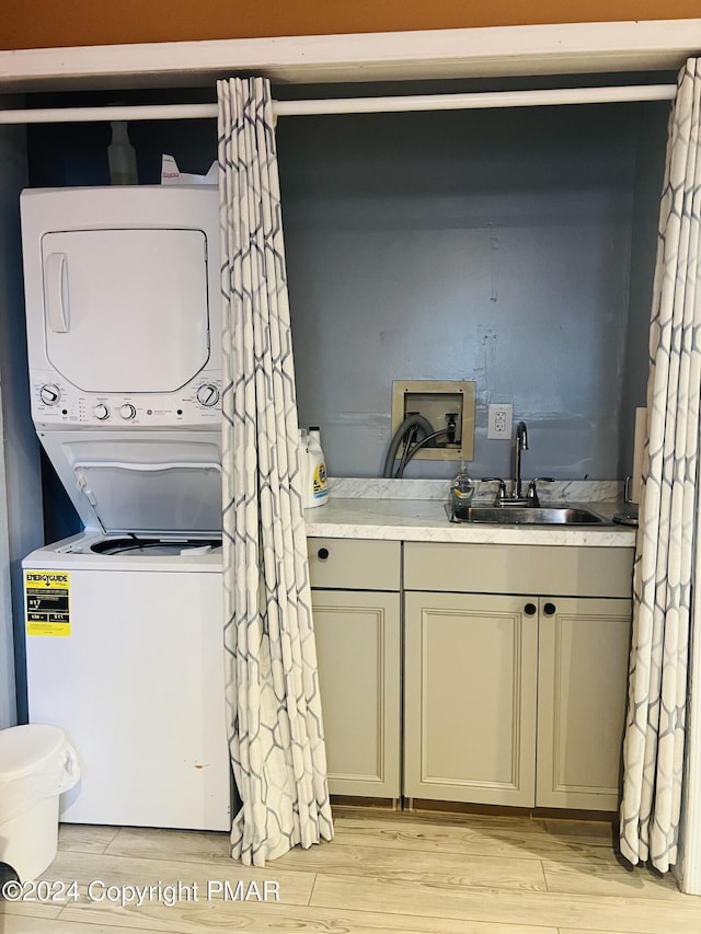 laundry room featuring stacked washing maching and dryer, laundry area, light wood finished floors, and a sink