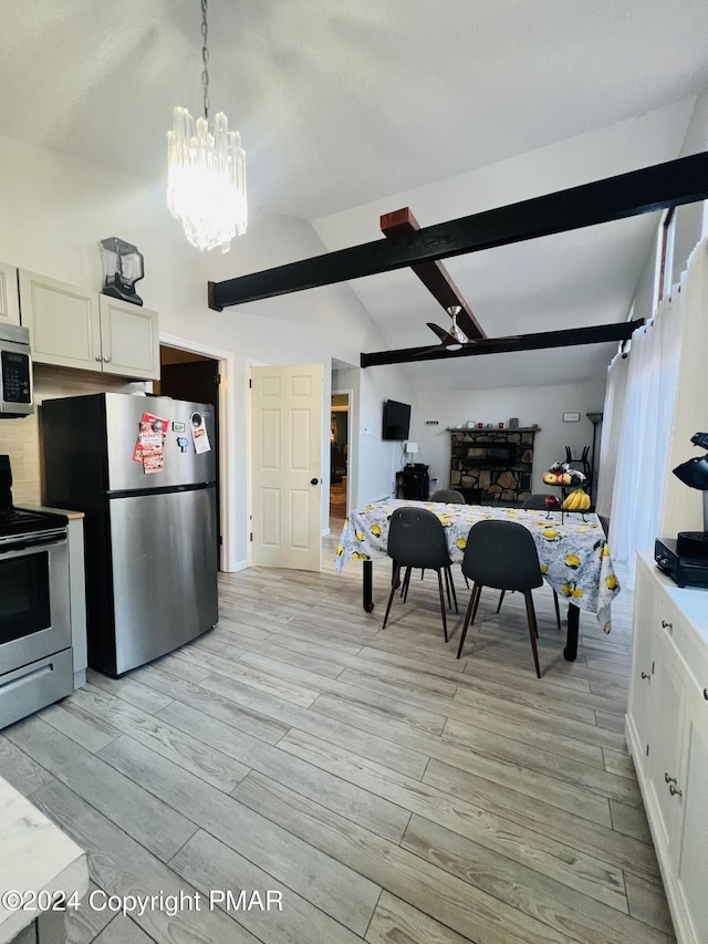 kitchen featuring vaulted ceiling with beams, appliances with stainless steel finishes, light wood-style floors, open floor plan, and white cabinetry