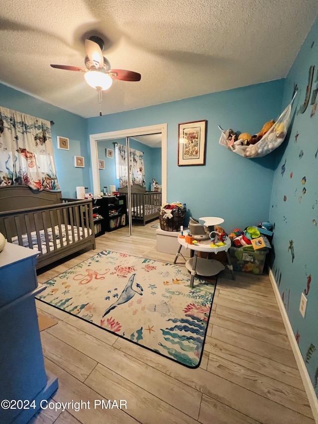 bedroom with a closet, ceiling fan, a textured ceiling, wood finished floors, and baseboards