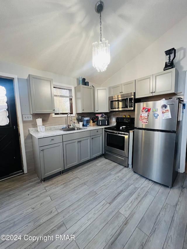 kitchen with stainless steel appliances, gray cabinets, a sink, and light wood-style flooring