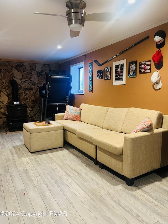 living area featuring a ceiling fan, a wood stove, and light wood finished floors