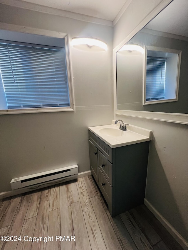 bathroom with crown molding, baseboard heating, vanity, wood finished floors, and baseboards