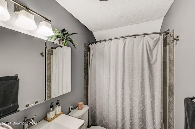 full bath with toilet, curtained shower, a sink, and a textured ceiling