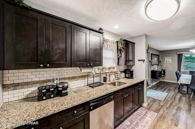 kitchen with light wood-style floors, dark brown cabinetry, a sink, and stainless steel dishwasher