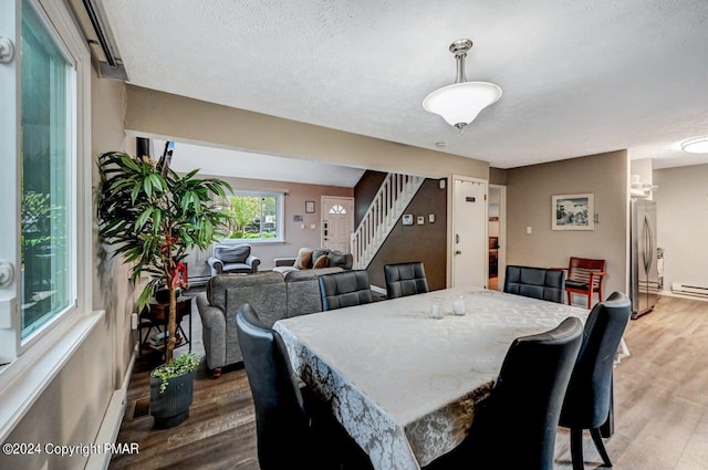 dining space featuring stairway, light wood-style flooring, and a textured ceiling