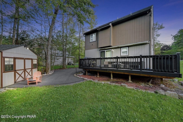 back of property with an outbuilding, a yard, a deck, and a shed