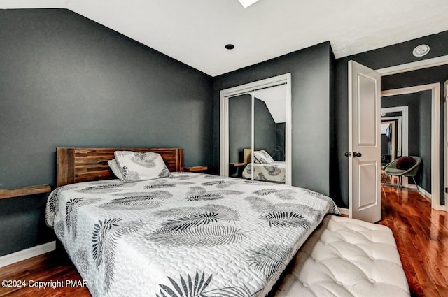 bedroom with vaulted ceiling, a closet, wood finished floors, and baseboards